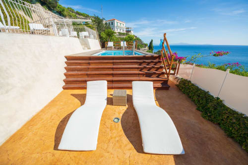 Due comode chaise longue bianche sulla terrazza di Villa Costanza a Maiori, con vista mare e vasca idromassaggio in legno