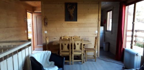 Intérieur rustique du chalet Cocody à Jausiers avec table à manger, coin salon et vue montagne depuis le balcon