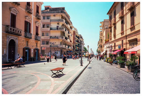 Piazza pedonale soleggiata a Maiori con edifici storici colorati, caffè e panchine vicino a Villa Costanza sulla Costa Amalfitana