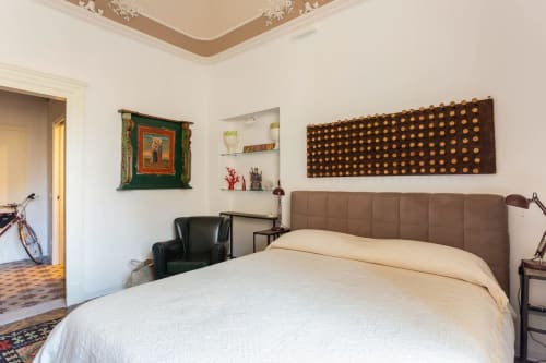 Camera elegante presso Sicilianinsta Rooms a Catania con testiera marrone, biancheria crema e decori artistici alle pareti