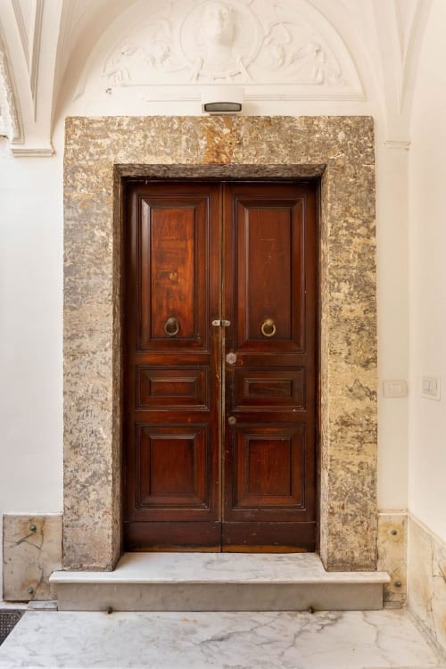 Eleganti doppie porte in legno massello di mogano scuro all'ingresso delle Sicilianinsta Rooms, edificio storico di Catania