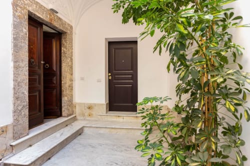 Elegante ingresso delle Sicilianinsta Rooms a Catania con porte in legno scuro, gradini in marmo e rigogliose piante rampicanti