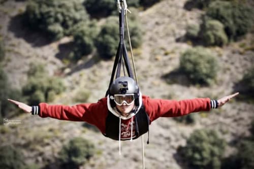 Persona practicando tirolesa sobre el paisaje de Sierra Nevada cerca de El Paraje del Chef, Granada