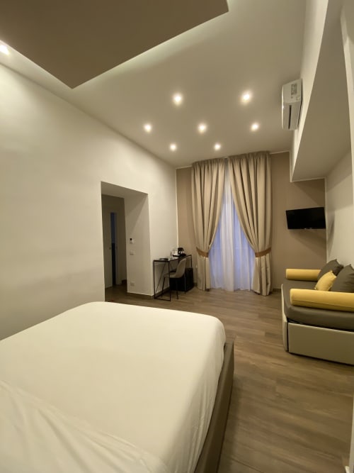 Deluxe-Familienzimmer im Salotto Toledo Neapel mit Bett, Sitzbereich, Schreibtisch und moderner Beleuchtung