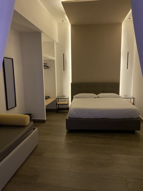 Luxusschlafzimmer im Salotto Toledo Neapel mit modernem schwarzem Bett, Ambientelicht, Holzböden und zeitgenössischem Design