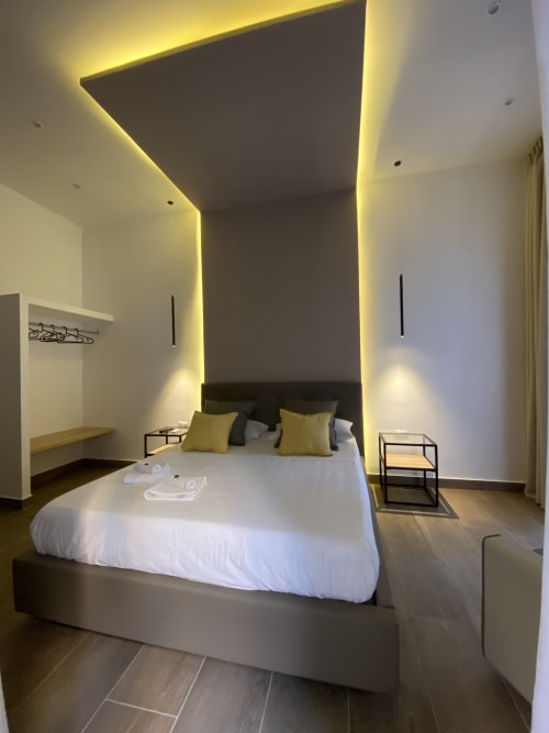 Luxuszimmer im Salotto Toledo Neapel mit Himmelbett, gelber Ambientebeleuchtung, moderner Einrichtung