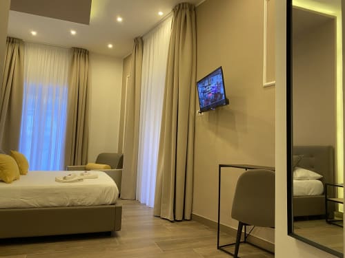 Luxuriöses Deluxe-Doppelzimmer im Salotto Toledo Neapel mit modernem Bett, eleganten Vorhängen, Wandfernseher und zeitgenössischem Design