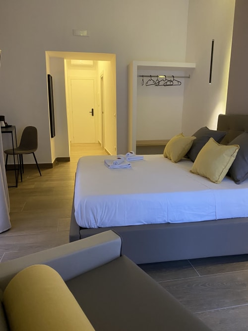 Deluxe-Zimmer mit Kingsize-Bett im Salotto Toledo, luxuriöses B&B in Neapel, mit Sitzbereich und gelbbeleuchteter Eingangshalle