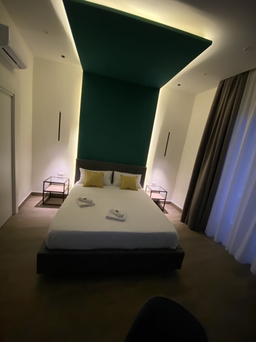 Modernes Superior-Zimmer im Luxushotel Salotto Toledo in Neapel, Italien mit grüner Akzentwand, Kingsize-Bett und zeitgenössischem Design