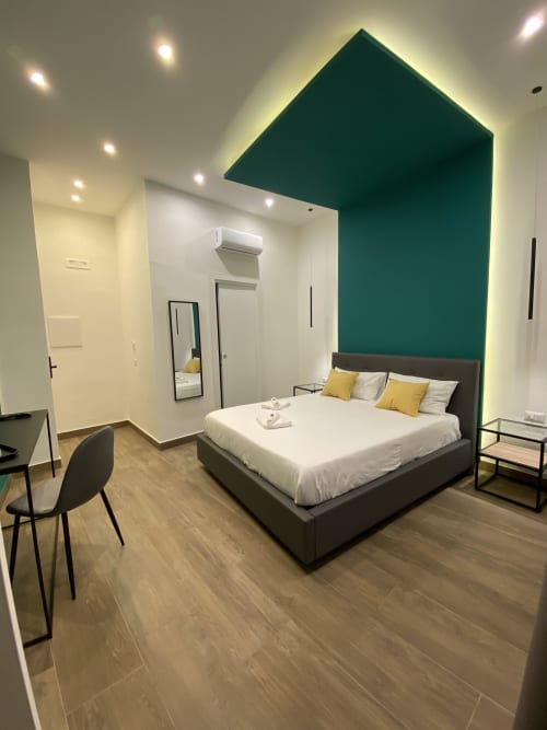 Modernes Superior-Zimmer im luxuriösen B&B Salotto Toledo in Neapel mit türkisfarbener Akzentwand, Queensize-Bett und zeitgenössischen Möbeln