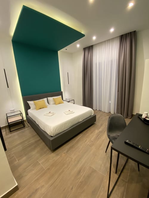 Modernes Superior-Zimmer im Luxushotel Salotto Toledo in Neapel mit Akzentwand in Türkis, Queensize-Bett und Stadtblick