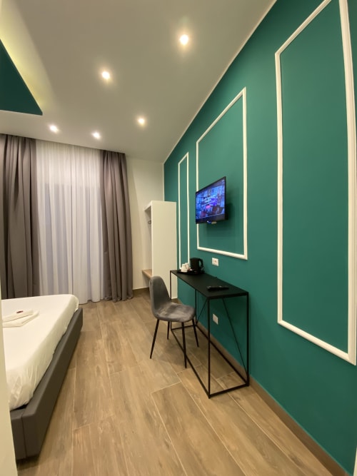 Modernes Superior-Zimmer im Salotto Toledo Neapel mit smaragdgrüner Akzentwand, Flachbildfernseher, Arbeitstisch und Holzfußboden