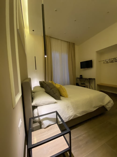 Modernes Schlafzimmer im luxuriösen B&B Salotto Toledo in Neapel mit Kingsize-Bett, gelben Akzenten, Flachbildfernseher und Stadtblick