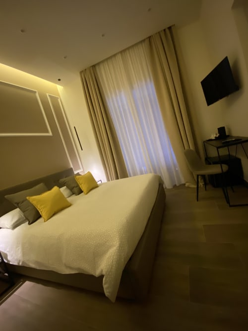 Modernes Standardzimmer im Salotto Toledo, luxuriöses B&B in Neapel, mit Queensize-Bett, gelben Kissen, Flachbildfernseher und Schreibtisch