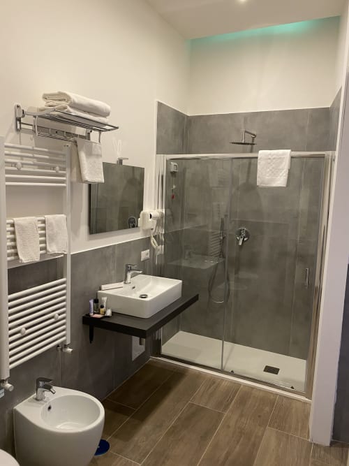 Modernes Badezimmer im Luxushotel Salotto Toledo in Neapel mit Regendusche, schwebendem Waschbecken, beheiztem Handtuchhalter und Grau