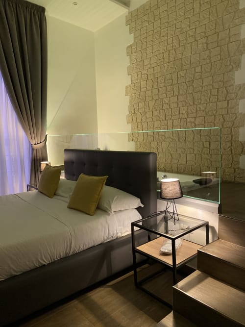 Modernes Luxus-Zimmer im Salotto Toledo Neapel mit schwarzem Bett, Backsteinakzentwand und verspiegelter Waschtischzone mit Stadtblick