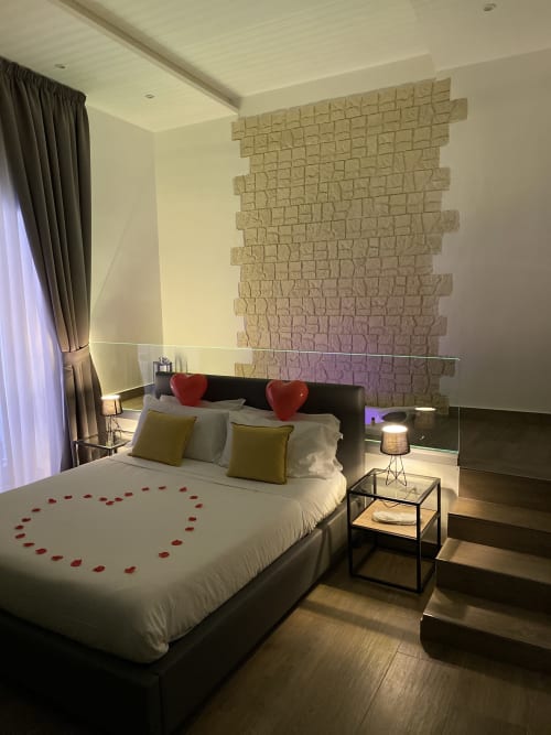 Luxus-Schlafzimmersuite im Salotto Toledo Neapel mit roter Herzdekoraion, Backsteinakzentwand und modernen Annehmlichkeiten