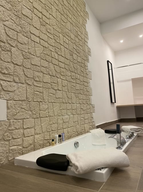 Luxuriöses Badezimmer im Salotto Toledo Neapel mit strukturierter Steinwand, weißer Badewanne und modernen Annehmlichkeiten
