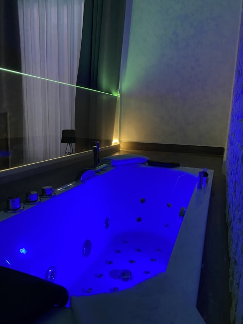 Luxus-Jacuzzi-Suite im Salotto Toledo in Neapel mit blauem beleuchteten Whirlpool und stimmungsvollem Licht