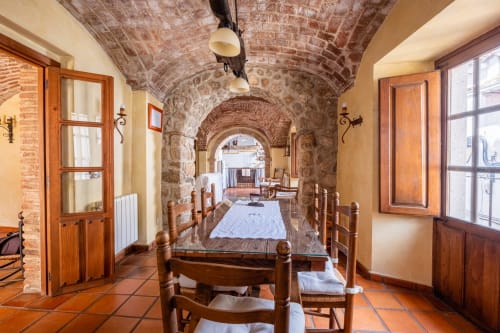 Comedor con bóveda de piedra, sillas y mesa de madera en Casa Rural El Fontano de Montánchez