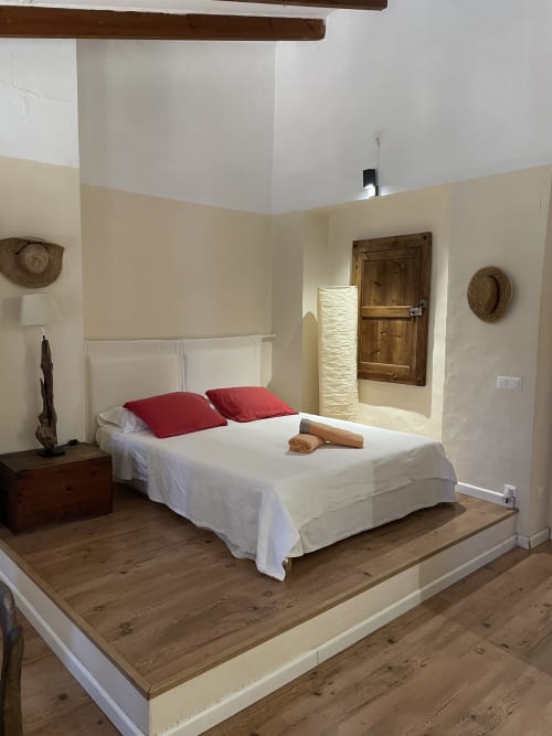 Habitación doble Tramuntana Superior del Petit Hotel Sa Plana en Estellencs, Mallorca, con cama de madera elevada, almohadas rojas y