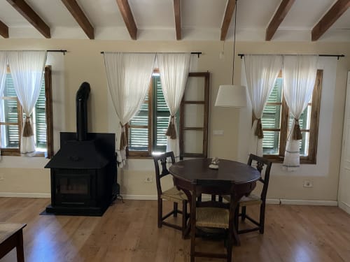 Habitación Tramuntana en Petit Hotel Sa Plana, Estellencs. Salón con mesa redonda de madera, chimenea y amplias ventanas