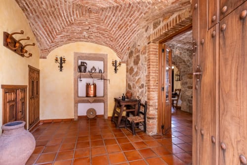 Interior rústico del hotel Casa Rural El Fontano en Montanchez con baldosas de terracota, arcos de ladrillo visto, puertas de madera y