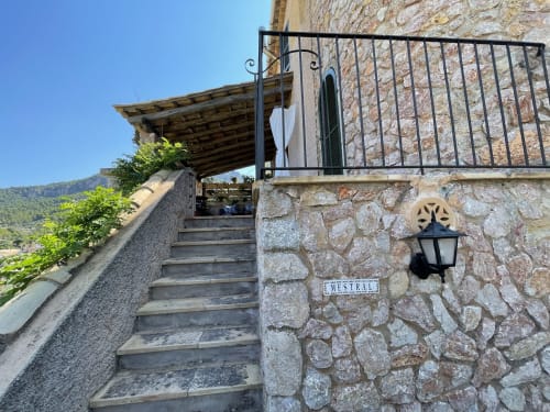 Entrada a la habitación Mestral del Petit Hotel Sa Plana en Estellencs con arquitectura de piedra y vistas al mar