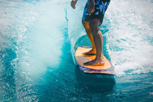 Surfista che cavalca le onde su una tavola da surf blu vicino a Torre Grande Oristano, Italia
