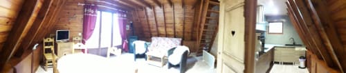 Intérieur de chalet en bois avec lit, coin salon, télévision et balcon avec vue sur les montagnes aux Chalets Cocody