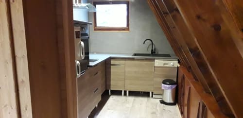 Cuisine moderne de la villa Chalet Cocody à Jausiers avec poutres en bois, évier en inox et électroménagers