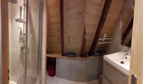 Salle de bain moderne de la villa Chalets Cocody à Jausiers avec baignoire îlot, douche, lavabo et poutres bois apparentes