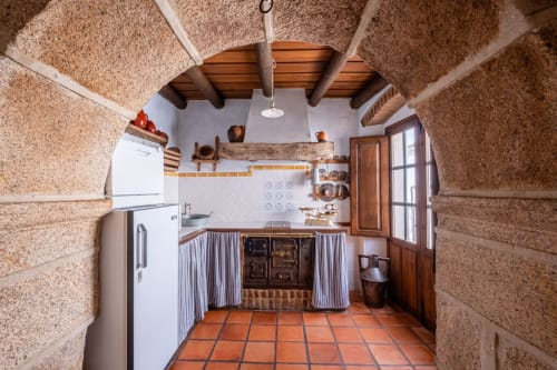 Rustic kitchen in Casa Rural El Fontano villa, Montanchez, with terracotta floor, cork walls, wooden beams, and white