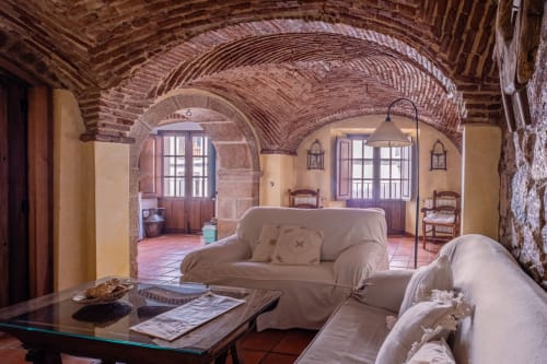 Rustic villa living room at Casa Rural El Fontano with brick arches, cream sofa, and terracotta floors in Montanchez