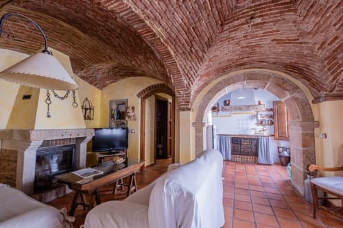 Rustic stone villa interior at Casa Rural El Fontano with arched brick ceilings, fireplace, and sitting area