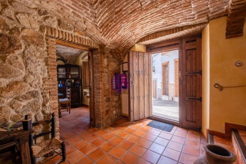 Rustic entrance hallway at Casa Rural El Fontano villa in Montanchez with terracotta tiles, exposed brick, and wooden doors