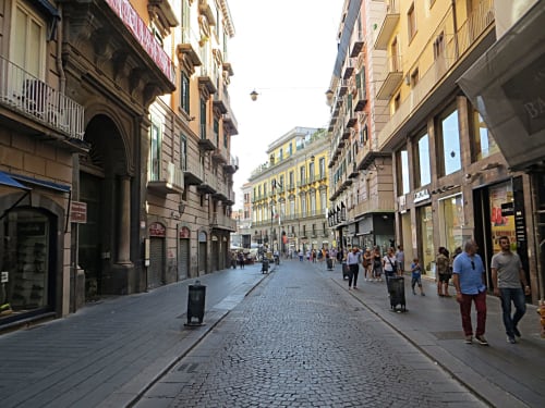 Vivace via pedonale a Napoli con edifici storici, negozi e abitanti vicino a Salotto Toledo