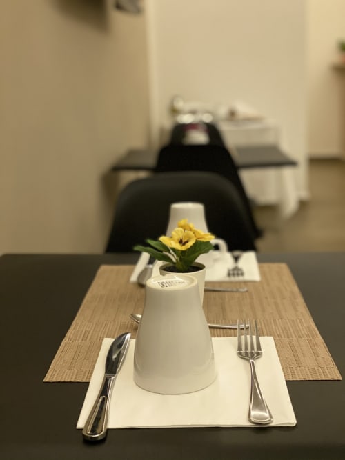 Elegante allestimento della sala da pranzo presso il B&B di lusso Salotto Toledo a Napoli, piatto bianco con fiore giallo in vaso, coperto formale