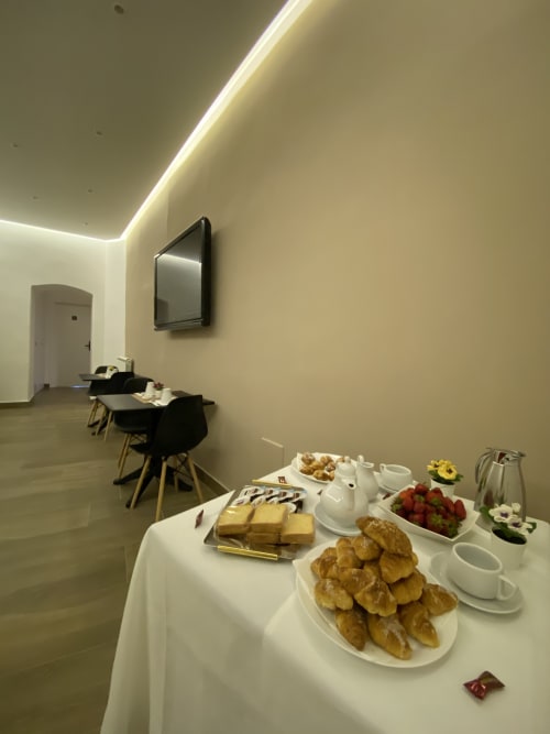 Colazione gourmet al Salotto Toledo, esclusivo B&B di Napoli, con pasticceria, frutta, formaggi e servizio caffè in camera moderna