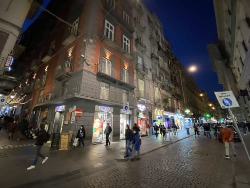 Scena serale vivace in strada presso Salotto Toledo luxury rooms a Napoli, con vetrine illuminate e pedoni