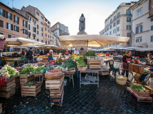 Vibrant Campo de' Fiori market in Rome with fresh produce, vendor stalls, and historic architecture near Orso Luxury