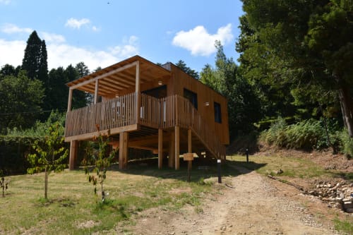 Cabaña de madera con terraza en Cabañas Compostela, rodeada de vegetación exuberante en Santiago de Compostela