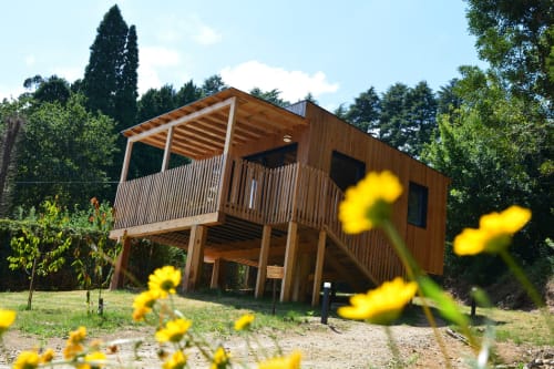 Cabaña de madera con terraza elevada y porche en Cabañas Compostela, Santiago de Compostela, rodeada de flores amarillas