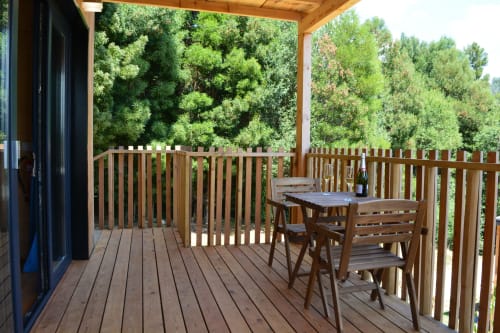 Terraza de madera con mesa de comedor con vistas al bosque en Cabañas Compostela, Santiago de Compostela