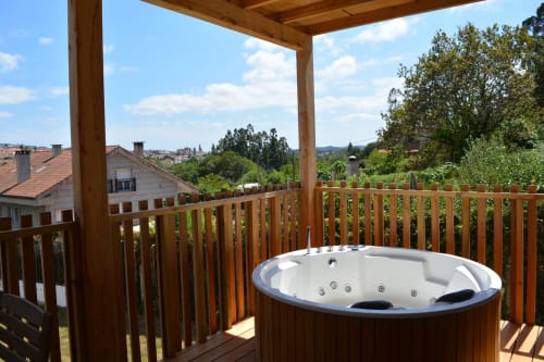 Bañera de hidromasaje al aire libre sobre terraza de madera con vistas a la montaña en Cabañas Compostela, Santiago de Compostela