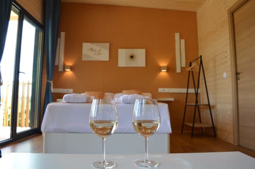 Dos copas de vino en la mesa de la terraza del apartamento Cabañas Compostela con dormitorio naranja y vistas a la ciudad, Santiago de Compostela