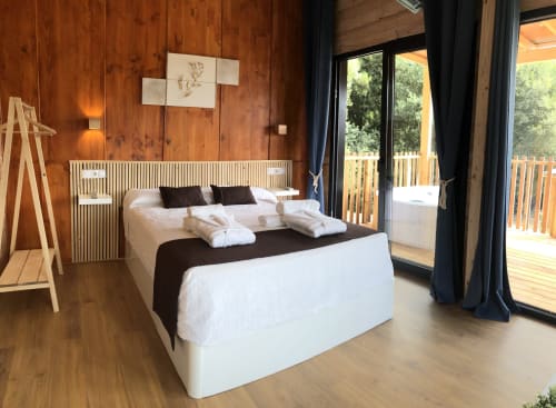 Habitación moderna en Cabañas Compostela con paredes de madera, cama blanca, acceso a terraza y vistas a la ciudad de Santiago de Compostela