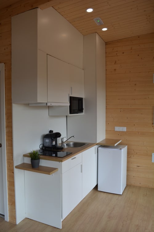 Cocina moderna con gabinetes blancos, encimera de madera, fregadero y electrodomésticos en Cabaña A Fervenza, Cabañas Compostela