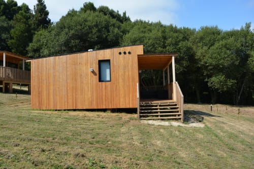 Moderna cabaña de madera en Cabañas Compostela con terraza y escaleras de acceso, rodeada de árboles en Santiago de Compostela