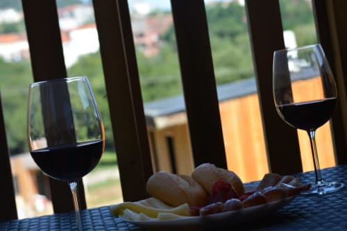 Copas de vino tinto y tabla de quesos en la terraza de Cabañas Compostela con vistas a las montañas, Santiago de Compostela